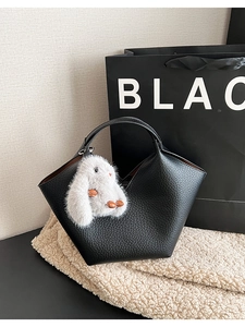 Détail d'un sac seau en cuir grainé noir orné d'un pendentif lapin en peluche blanche