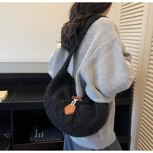 Detail of black fuzzy hobo bag featuring a wooden horn button and leather patch accent
