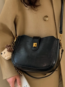 Classic black matte leather bucket bag with gold hardware and plush puppy charm