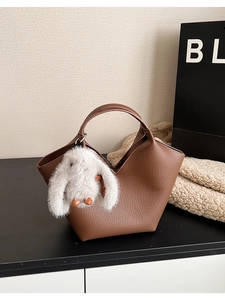 Gros plan d'un sac à main marron en cuir grainé avec un charmant lapin blanc