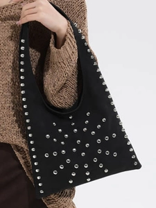 Vintage black suede tote bag with silver studs and a wide shoulder strap worn by a model