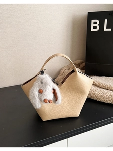 Gros plan d'un sac à main beige grainé avec une adorable peluche de lapin suspendue