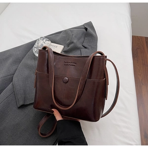 Détail d'un sac seau vintage en cuir marron foncé avec fermoir magnétique et texte décoratif