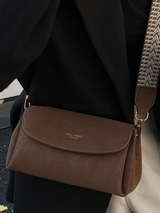 Sac à bandoulière marron vintage avec finition texturée et bandoulière rétro sur un manteau