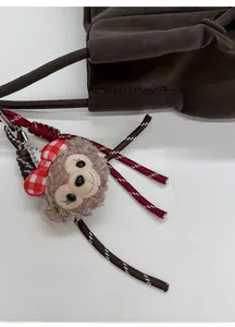Détail d'un pendentif en peluche avec nœud sur un sac cabas en cuir marron foncé