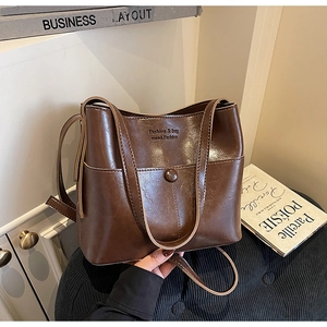 Gros plan détaillé d'un sac cabas en similicuir marron foncé brillant avec logo gravé