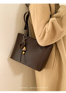 Detail view of a dark brown leather bucket bag with a retro mini headphone charm