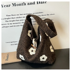 Detail of plush tote bag showing white floral embroidery and wooden toggle button closure