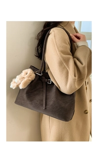 Detail of vintage brown tote bag featuring a cute bunny plush charm and side strap buckle