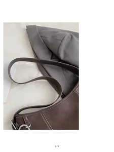 Dettaglio della borsa tote vintage in pelle marrone con cuciture bianche e fibbia in metallo