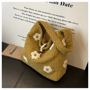 Detail view of mustard yellow plush tote featuring wood toggle closure and floral embroidery