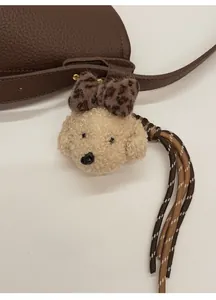 Close-up of a plush dog bag charm with leopard bow and braided rope detail