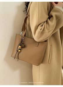 Detail of tan leather bucket bag with creative mini headphone charm and beaded pendant