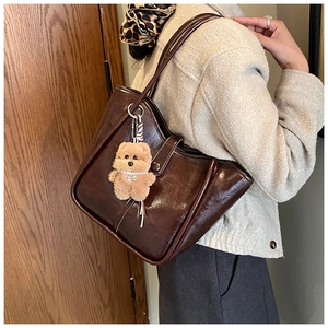 Detail of dark brown faux leather shoulder bag with cute teddy bear and pearl charm