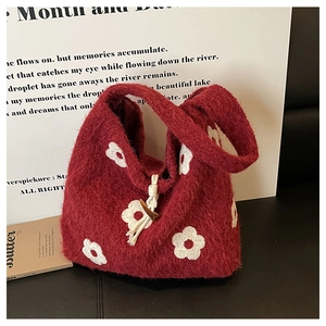 Close-up of red plush tote bag with white floral embroidery and wooden toggle closure