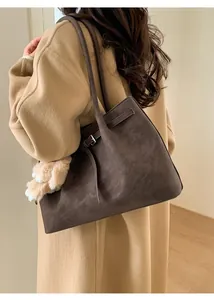 Detail of vintage brown tote bag with suede texture and plush pendant for winter style
