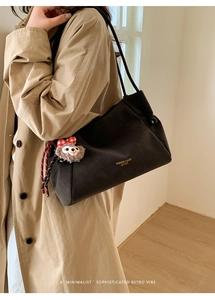 Détail du sac cabas en cuir noir mat avec nœuds à cordon et un pendentif agneau en peluche