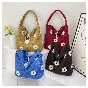 Detail view of plush flower embroidery tote bags in four vibrant colors on a stand