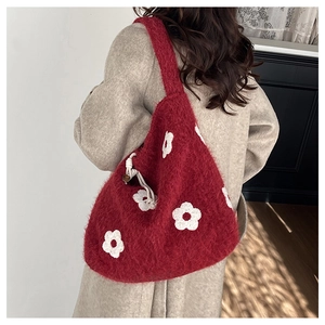 Detail of red plush knit tote with floral embroidery and white drawstring on shoulder bag