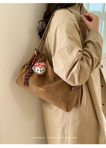 Détail du sac fourre-tout en daim marron avec charm ours en peluche et cordon tressé