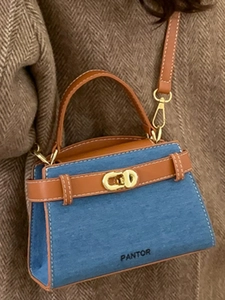 Blue denim and brown leather mini tote handbag with gold lock on a winter coat