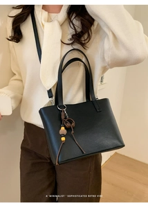 Dettaglio di una borsa a secchiello in pelle nera con ciondolo retrò in perline di legno