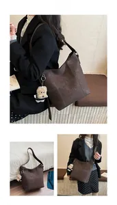 Dettaglio della borsa tote marrone scuro con cuciture bianche e ciondolo a cucciolo