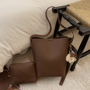 Detail of dark brown lychee texture bucket bag with cute plush bear keychain