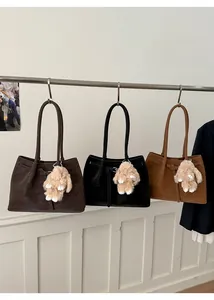 Detailed view of large leather tote bags in dark brown, black, and tan with plush charms