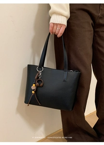 Close-up of black leather bucket bag with headphone pendant and beaded charm detail