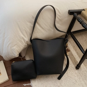 Detail of black lychee grain bucket bag with matching pouch and leopard fur ball charm