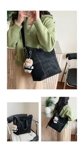 Dettaglio della borsa tote vintage nera con cuciture a contrasto e ciondolo a orsetto