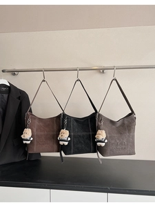 Dettaglio del tessuto in ecopelle della borsa tote con scritta in rilievo e ciondolo
