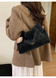 Détail du sac fourre-tout en velours noir avec lettrage doré et charme de singe