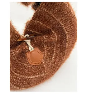 Close-up of brown plush knit bag with decorative leather patch and toggle horn button