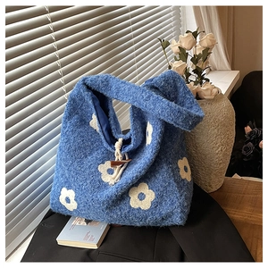 Detail of blue plush tote bag featuring floral embroidery and a wooden toggle closure