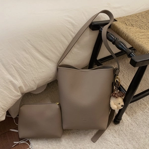 Detail of taupe bucket bag with litchi texture leather and a cute plush bear charm
