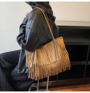 Détail du sac cabas en daim marron chameau avec doubles franges porté à l'épaule