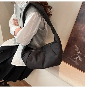 Detail of black puffer crossbody bag featuring soft padded nylon and silver zipper