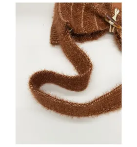 Detail of wide knitted shoulder strap on a brown plush tote bag with toggle button