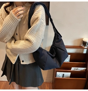 Detail shot of navy blue puffer crossbody bag with quilted texture and wide shoulder strap