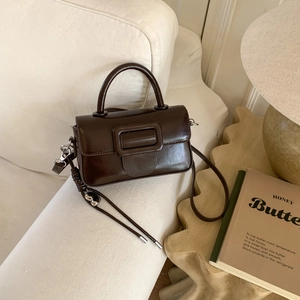 Detailed view of the vintage brown crossbody bag on a sofa with warm lighting