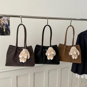 Detailed view of three large leather tote bags in dark brown, black, and camel with rabbit charms