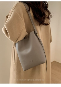 Detailed view of grey pebble leather bucket bag showing logo and gold-tone hardware