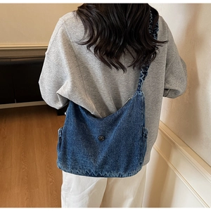 Blue denim half-moon crossbody bag with ruffled cloud strap and M metal buckle on model