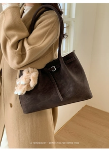 Macro view of retro brown suede tote bag featuring silver buckle and plush bunny charm