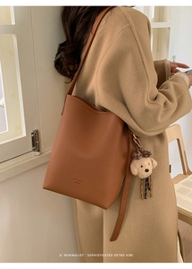 Close-up of brown bucket bag with lychee texture and cute plush dog charm detail