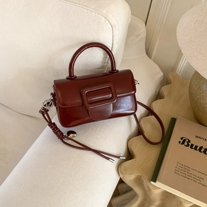Detailed close-up of a burgundy leather mini handbag on a sofa in a warm home setting
