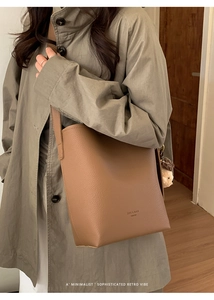 Detail of dark brown leather bucket bag with litchi texture and cute bear pendant