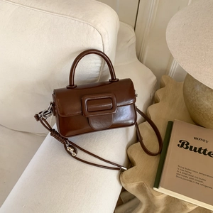 Detailed close-up of brown vintage leather handbag on a soft white sofa set